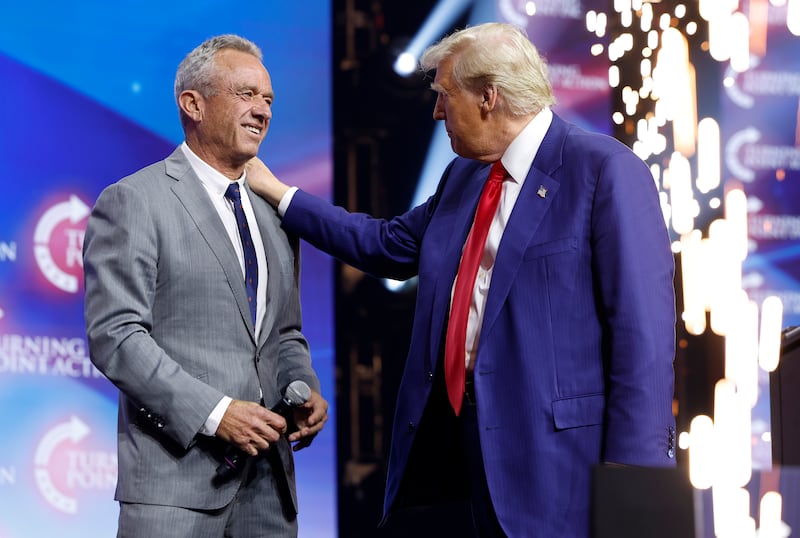 Republican presidential nominee, former U.S. President Donald Trump welcomes Robert F. Kennedy Jr. to the stage at a Turning Point Action campaign rally at the Gas South Arena on October 23, 2024 in Duluth, Georgia.