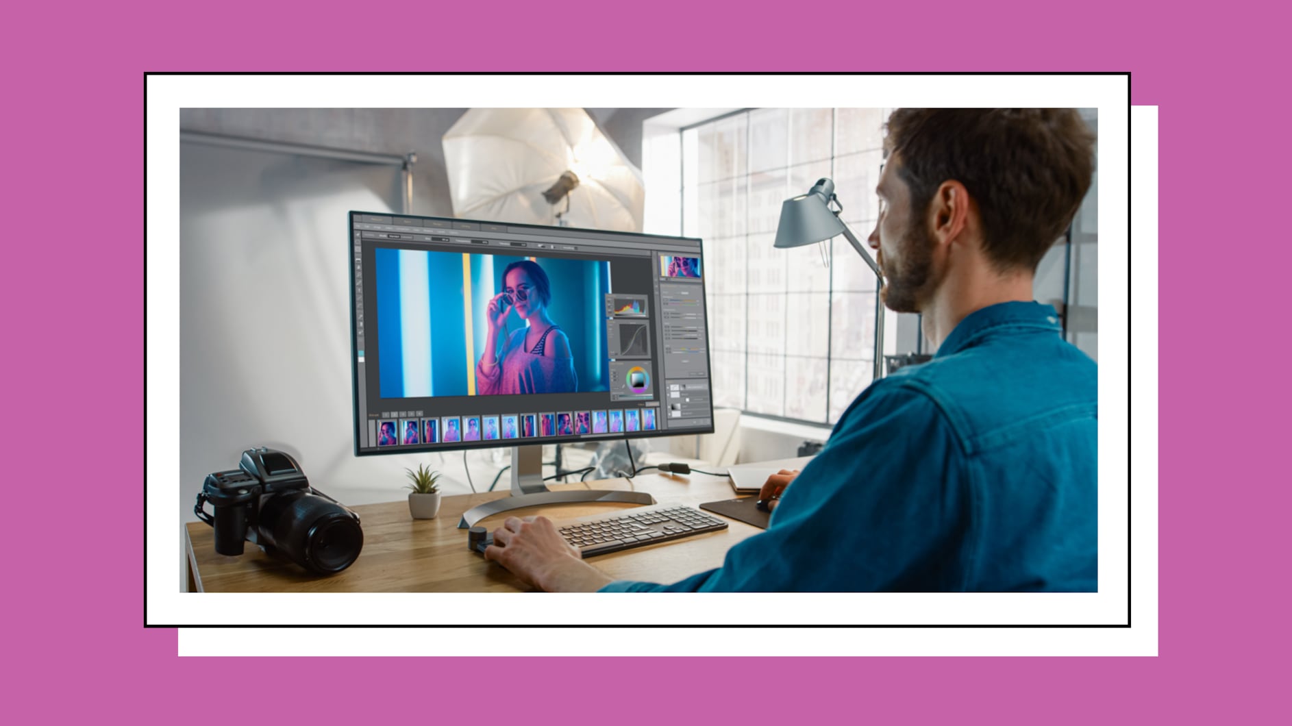 Man using Adobe Photoshop on a desktop in a well-lit office. He has a camera and lamp beside him.